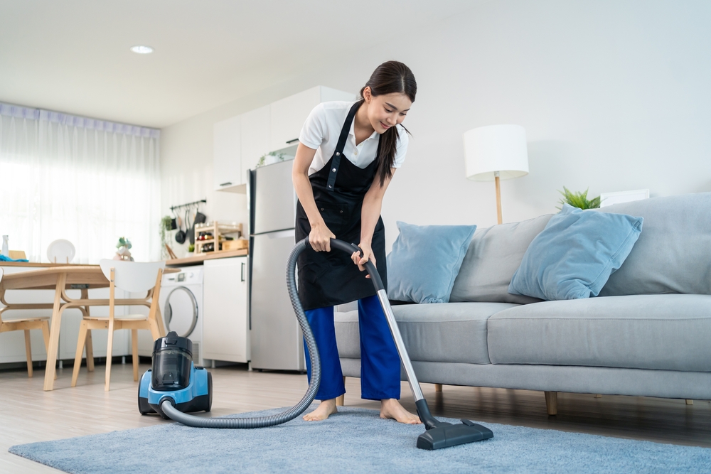 perempuan menggunakan vacuum cleaner